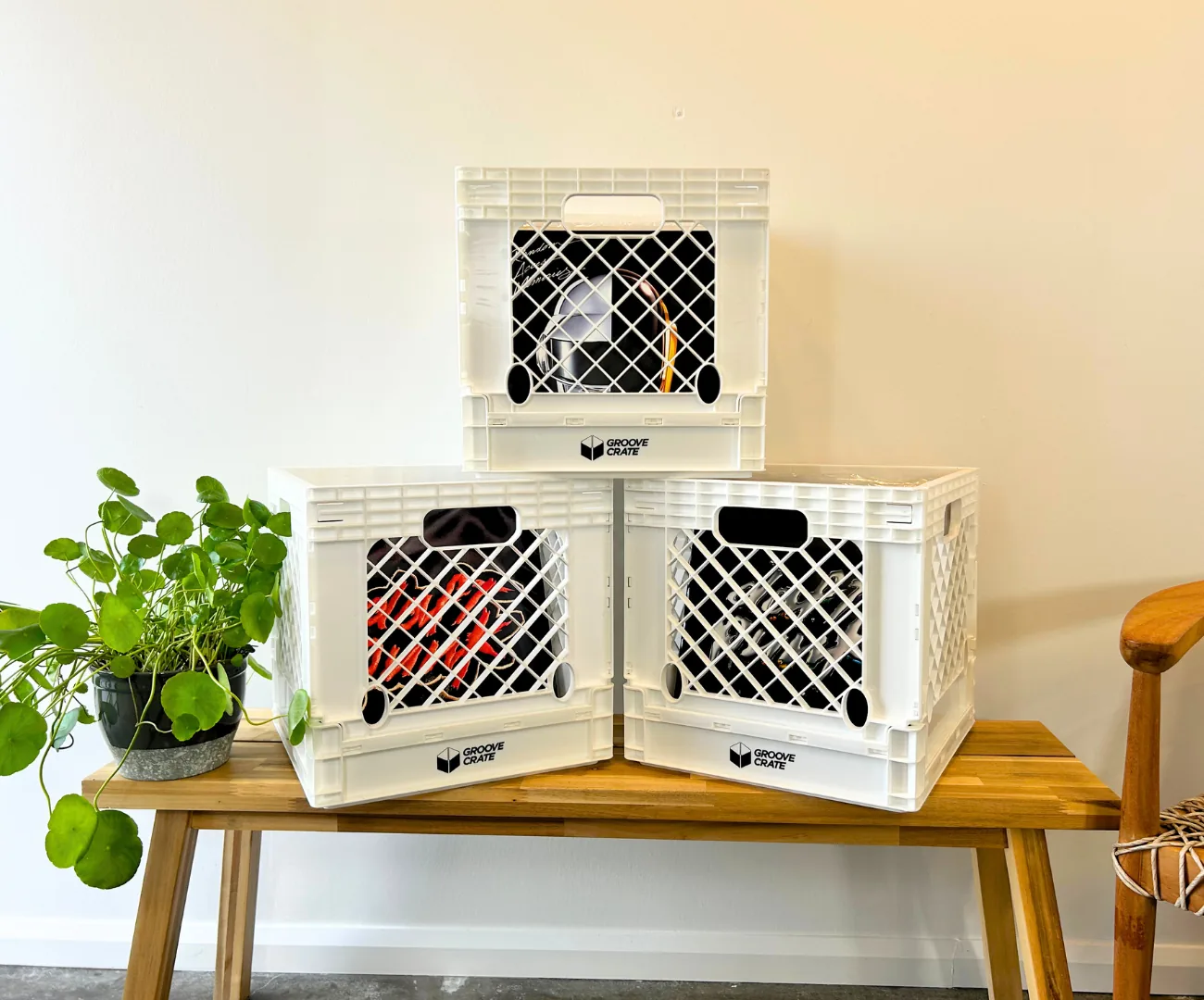 Three black Groove Crates filled with 12-inch vinyl records on a wooden bench